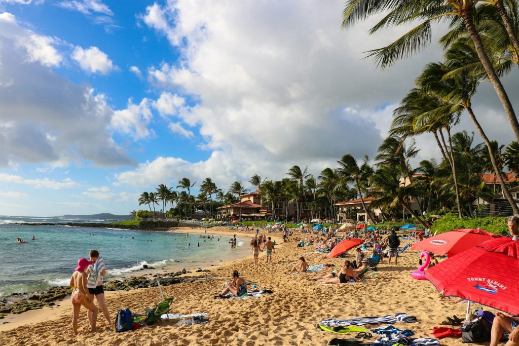 Sunbathers and umbrellas on the sandy shore of Poipu Beach Park, Kauai.