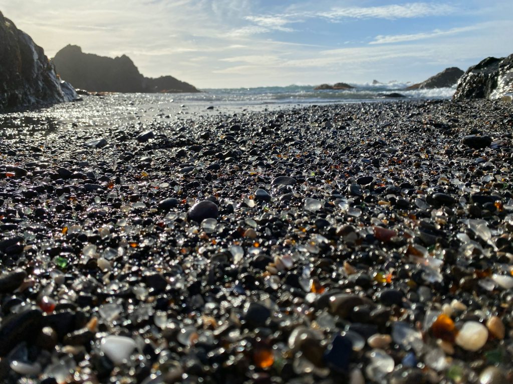 Close-up of colorful sea glass pebbles and smooth stones on a rocky shoreline.