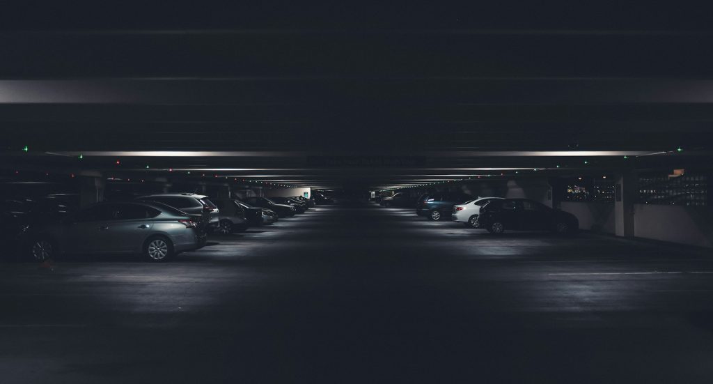 Cars parked in a dimly lit multi-level parking garage at night.