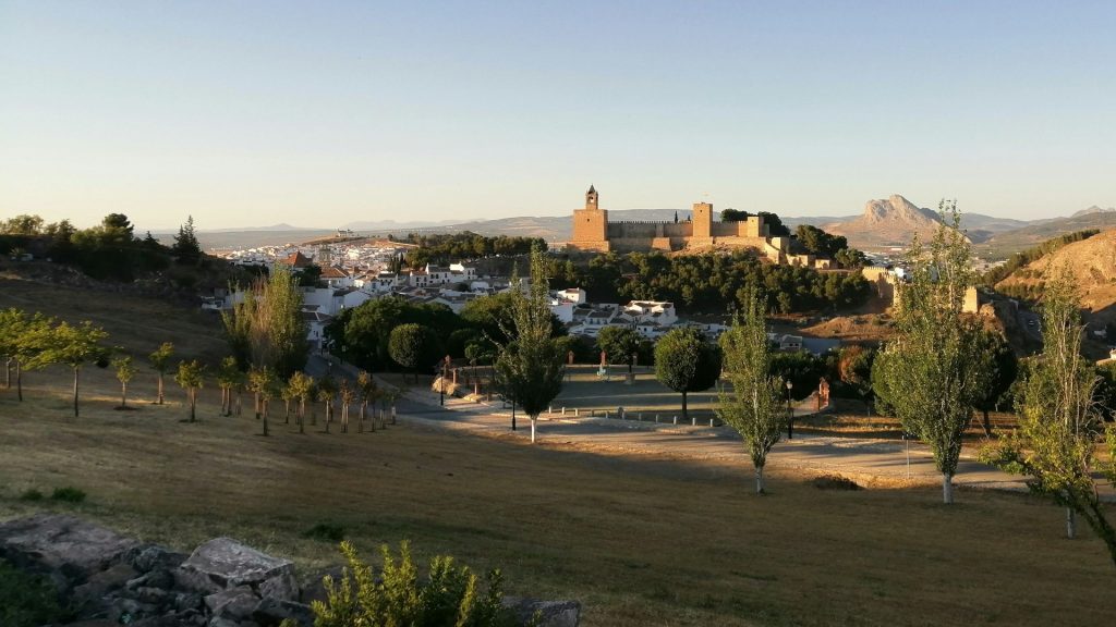 Panoramic view of Antequera with its Moorish Alcazaba fortress, white houses and rocky landscape at sunset.