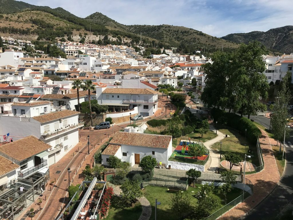 Aerial view of Benalmádena's white houses with terracotta rooftops and green hills in the background.