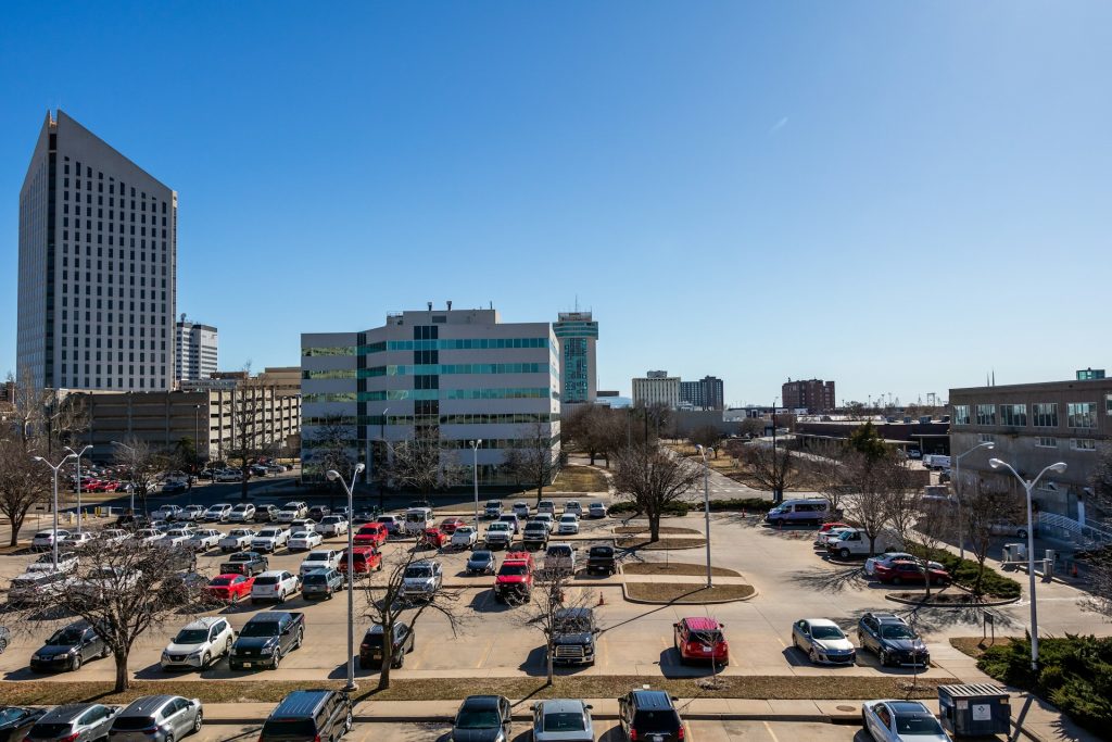 Large outdoor parking lot with cars near Kansas City's downtown office buildings under a blue sky.