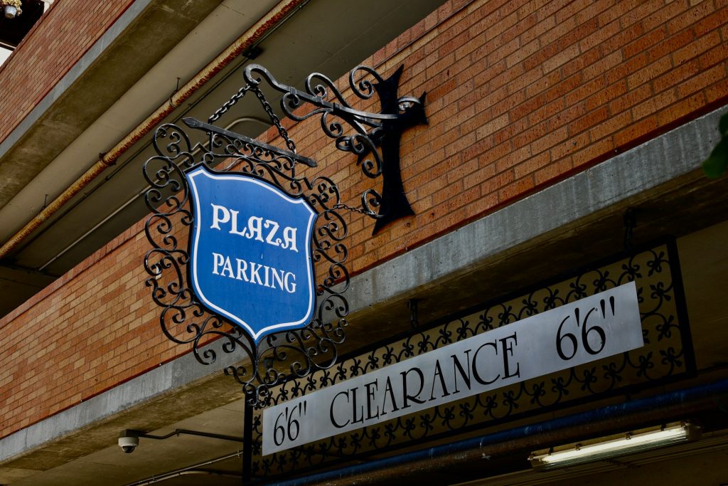 Ornate blue Plaza Parking sign with wrought iron details on a brick wall in Kansas City.