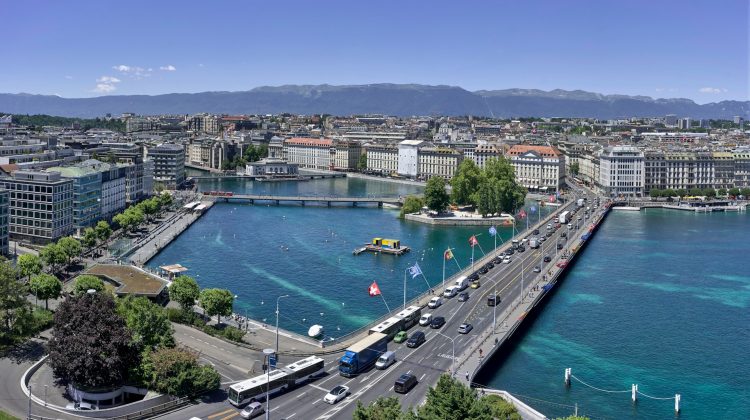 Aerial view of Geneva with its turquoise lake, bridges, waterfront promenade and Alpine mountains.